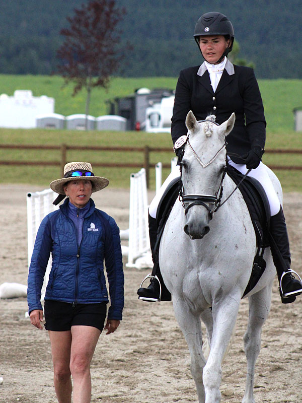 Riding instructor Mary guiding a rider on a white horse during a training session.