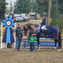 Richard and presenter with Mary on a bay horse posing with a large blue "Area VII Championships" winner's ribbon.